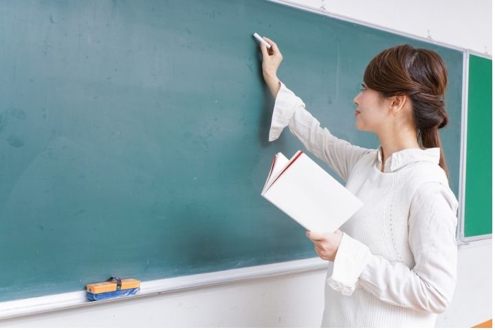 女性教師が黒板に書記している様子