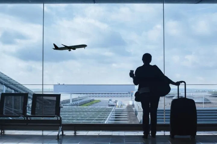 キャリーケースを持って空港にいるイメージ