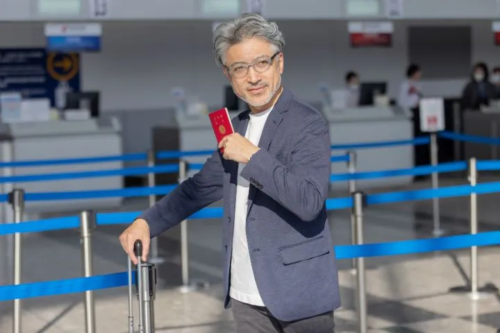 パスポートとキャリーケースを持って歩く男性のイメージ