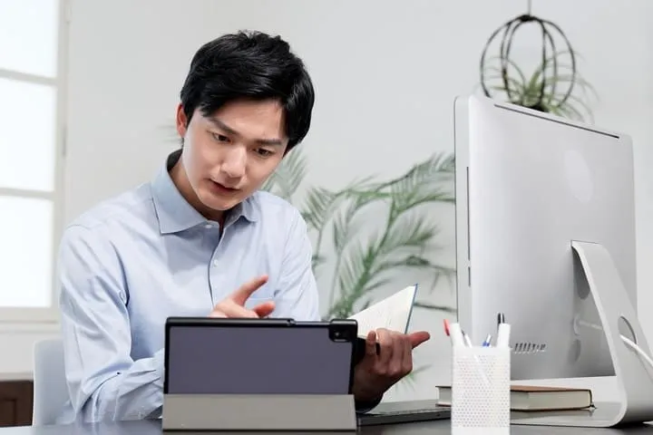 タブレットと書類を見比べる男性の画像