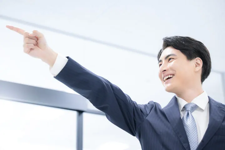 明るい顔で指をさす若者の画像