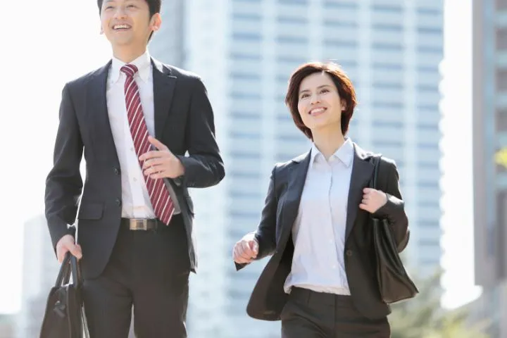 ビジネス街を走る共働きの夫婦のイメージ画像