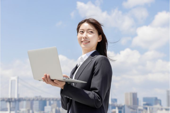 パソコンを持ち笑顔の女性の画像