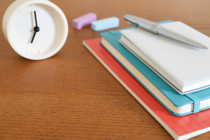 時計とノートとペンが置かれた画像