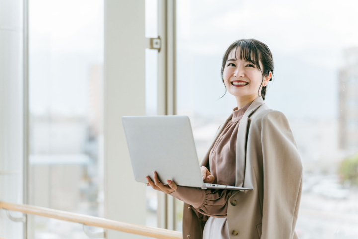 PCを持ち笑顔の日本人女性の画像