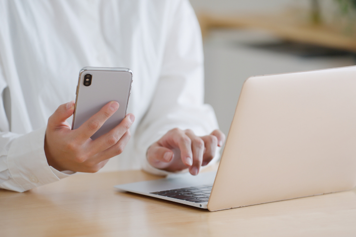 スマホを片手にパソコンを使う女性の手元の画像