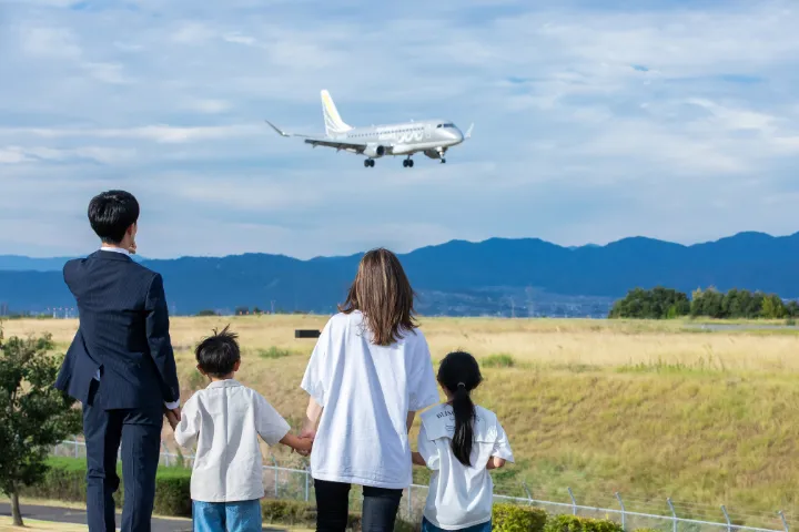 飛行機を見つめる4人家族の後ろ姿の画像