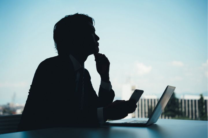 ノートパソコンを開き考える男性のイメージ