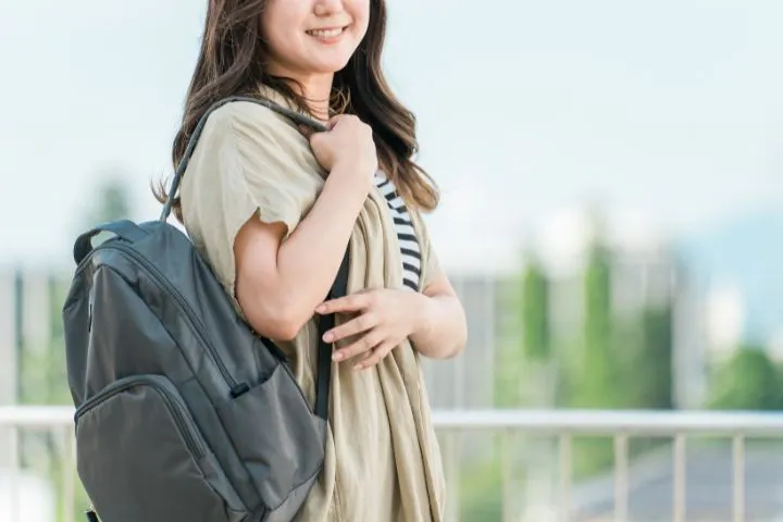 リュックを背負ってほほ笑む女性のイメージ