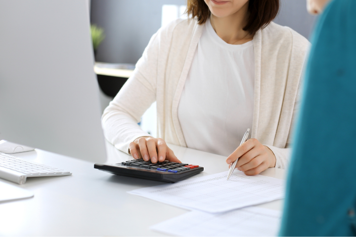 資料を見ながら電卓で計算している女性のイメージ