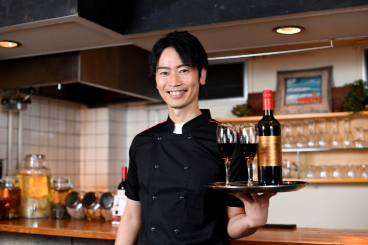 ワインとグラスを持つ笑顔の日本人ウェイターの画像