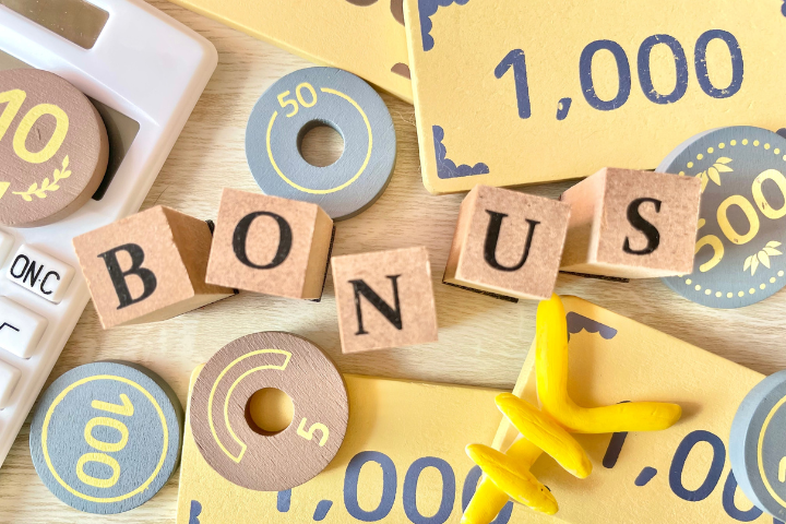 ボーナスと書かれたブロックとおもちゃのお金の画像