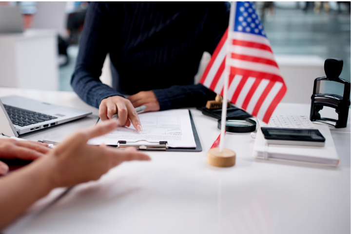 アメリカの国旗の前で手続きをする人の手の画像