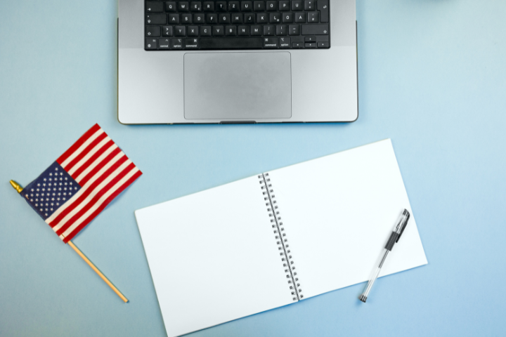 メモ帳とアメリカ国旗とノートパソコンの画像