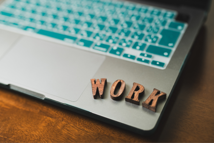 パソコンの上に木で出来たworkの文字が置かれた画像