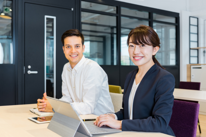 スーツ姿の外国人男性と日本人女性が笑顔でこちらを向いている画像