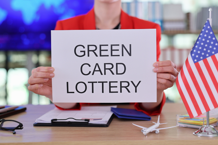 GREEN CARD LOTTERYと書かれた紙を持った女性のイメージ