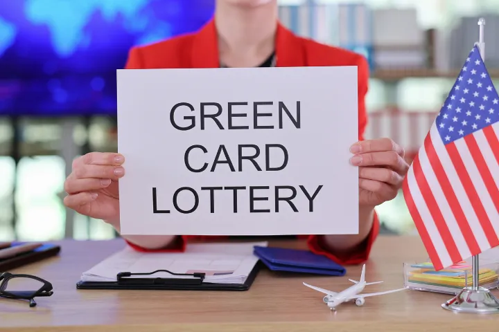 GREEN CARD LOTTERYと書かれた紙を持った女性のイメージ