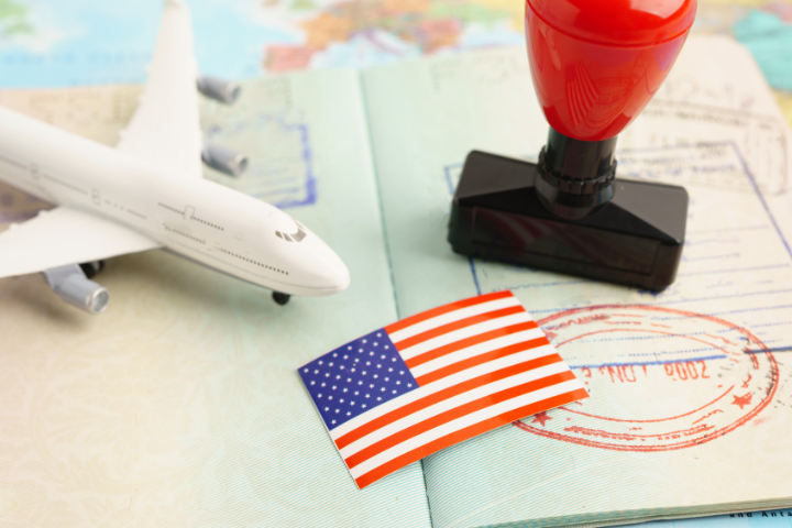 パスポートの上にあるおもちゃの飛行機、スタンプ、紙のアメリカ国旗のイメージ