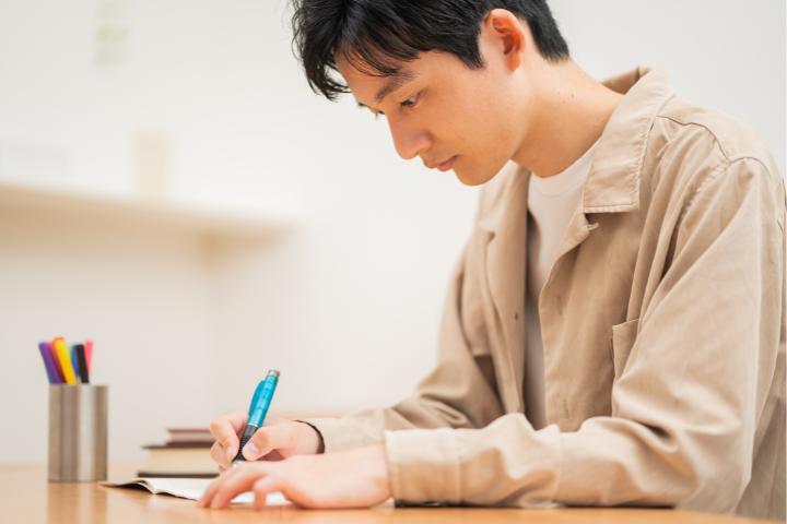 机に向かって勉強をしている男性の画像