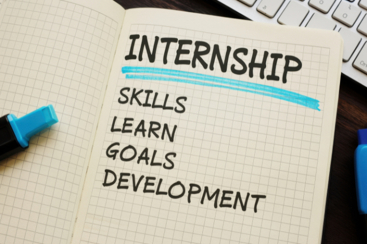 「INTERNSHIP」という単語が青色でハイライトされたノートと、「SKILLS」「LEARN」「GOALS」「DEVELOPMENT」という単語のリストが置かれている画像